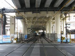 駅の横浜方にある踏切から駅構内を見る。右へ分岐する線路が空港線ホームへ通じる。この平面交差もまもなく解消される。