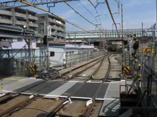 小島新田駅方面を見る。奥の高架橋が首都高速1号横羽線で、その下が産業道路と交差する踏切。