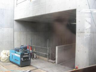 壁面が透明になっている部分から工事中の本設通路を見る。コンクリートの仕切りはエスカレータ用？