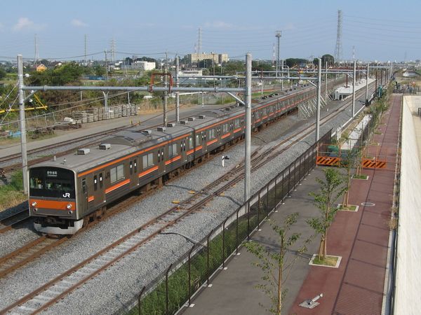 工事中のホーム脇を通過する武蔵野線上り列車。手前のバラストが白い線路が新上り本線。